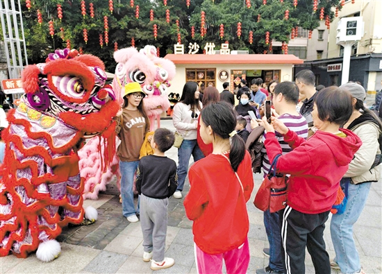 游客在長(zhǎng)堤歷史文化街區(qū)與醒獅合影。何雯意